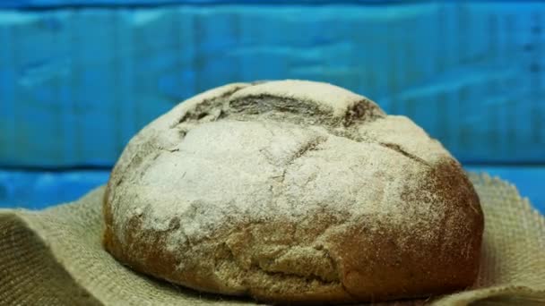 ターンテーブルの青い板の背景に新鮮なパンのクローズアップ 袋入り自家製パン — ストック動画