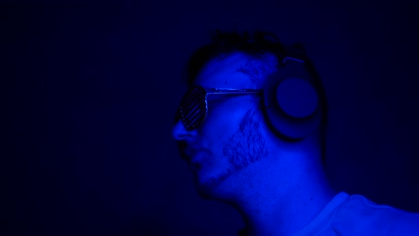 Tło Muzyczne Neonowym Błękicie Mężczyzną Słuchawkach Kreatywnych Okularach Klubowych Młody — Wideo stockowe