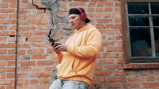 Genç Adam Evin Yakınında Duvarında Çatlak Olan Kulaklıkla Müzik Dinliyor — Stok video