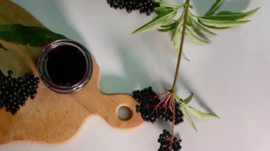 Tıbbi bir kavanozda kırmızı böğürtlen tentürü. Tahtada böğürtlen suyu, kara dut..