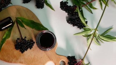 Kırmızı böğürtlen tentürü tıbbi bir kavanozda kamera hareketi. Tahtada böğürtlen suyu, kara dut..