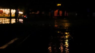 Yağmurlu bir gece şehriyle güzel bir arka plan. Yağmur, gece şehrinin su birikintilerine damlıyor..