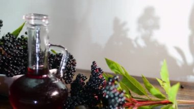 Mürver suyu bardakta, olgun siyah mürver meyvesi masada. Devamlı olmayan tıbbi böğürtlen