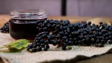 Doğal mürver suyu. Ahşap bir arka planda siyah mürver. Bitkisel ilaçlar. Homeopati, eski bir masada kara dut.