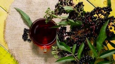 Kırmızı böğürtlen çayını yakın planda, ahşap bir masanın üst manzarasında. Mürver çayı. Vitaminler ve doğal çay. Çay hayat dolu.