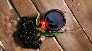 Üst manzara. Antika ahşap bir masada cam bir fincanda doğal kırmızı çilek çayı. Siyah mürver böğürtleninden çilek çayı. Böğürtlenli Sambucus Nigra 'dan sıkılmış Homeopati suyu