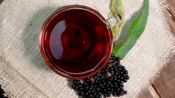 顶部景观天然红莓茶在一个玻璃杯在一个旧的袋与浆果枝 黑接骨木新鲜的浆果茶 顺势疗法草药茶 — 图库视频影像
