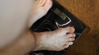 Adamın ağırlık kontrolü, adamın bacakları zemin terazisinde duruyor, 95.6 kg adam, obezite ve aşırı kilolu adam.