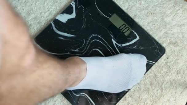 体重管理 男性は床のスケールに立つ 男76 7キロ 肥満と太りすぎの男 — ストック動画