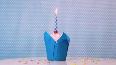 Mavi arka planda yanan bir mum olan, şenlikli mavi bir çöreğin yakın çekimi. Her yaş için doğum günün kutlu olsun. Kremalı kek. Yıldönümü arkaplanı