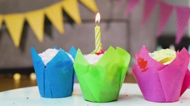 Çok renkli renkli muffinlerin, yanan bir mumla yakın çekimi. Her yaş için mutlu yıllar.