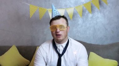 Elinde maytap olan bir adam. Şapkalı genç bir adam doğum gününü üzgün bir yüzle kutluyor. Ucube, tişörtlü bir kutlama adamıdır.