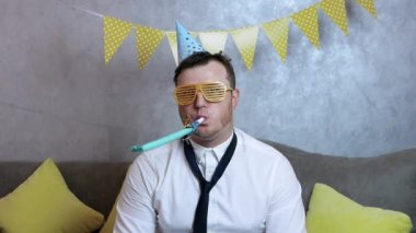 Genç bir adam için üzücü bir doğum günü, genç bir adam bir doğum gününü ya da başka bir bayramı kutlayan neşeli bir melodi çalar. Tatil çelenkleriyle ofiste sıkılmış bir adam.