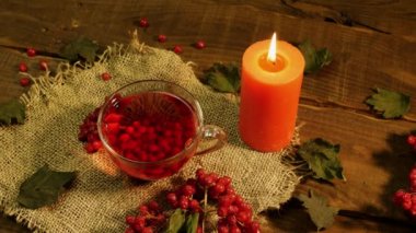  Kırmızı çay ve yanan mumlarla arka plan fincanı. Kırsal panolardaki kırmızı viburnum üzümünün doğal çayı. Naturopati çilek tedavisi.