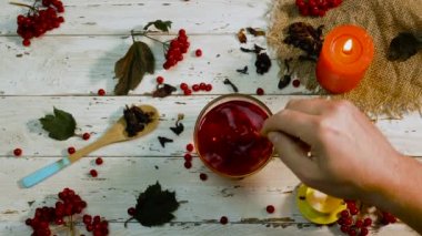  Çay kaşığıyla çayı karıştır. Viburnum 'dan doğal çilek çayı. Fincanın üstünde sıcak kırmızı çay.