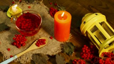 Kırmızı çay ve yanan mumlarla arka plan bardağı. Kırsal panolardaki kırmızı viburnum üzümünün doğal çayı. Naturopati böğürtlen tedavisi. Antioksidan çayı.
