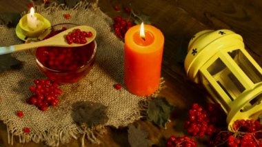 Kırmızı çay ve yanan mumlarla arka plan bardağı. Kırsal panolardaki kırmızı viburnum üzümünün doğal çayı. Naturopati böğürtlen tedavisi. Antioksidan içeceği. Çay ve mumlarla meditasyon için arka plan
