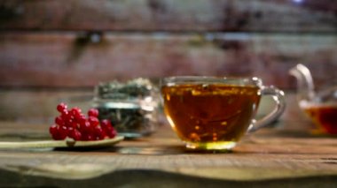 Yavaş çekimde şeffaf cam bardakta çay ve çaydanlık. Doğal bitki çayı. Kırmızı viburnum üzümlü terapötik naturopati çayı.
