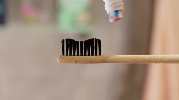 歯磨き粉は歯ブラシに適用されます 浴室のボケの背景をクローズアップしました 歯の洗浄コンセプト チューブから歯磨き粉を絞り出す — ストック動画