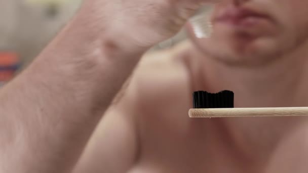 一个年轻人在浴室的牙刷上挤牙膏 一个手里拿着牙膏的男人白牙概念 — 图库视频影像