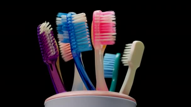 Close Toothbrushes Glass Rotate Black Background Caring Teeth Multicolored Toothbrushes — Stock Video
