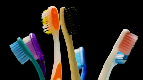 ガラスの歯ブラシのクローズアップは 黒の背景に回転します 歯のケア 多色の歯ブラシ ターンテーブル上の歯ブラシ 歯科治療 — ストック動画