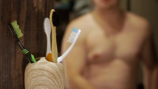一个年轻人在浴室的牙刷上挤牙膏 一个手里拿着牙膏的男人刷白牙齿的概念 — 图库视频影像