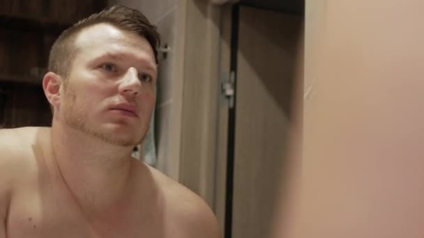 英俊的年轻人在镜子前的浴室里用木制牙刷刷牙 一个手里拿着牙膏的男人刷白牙齿的概念 — 图库视频影像