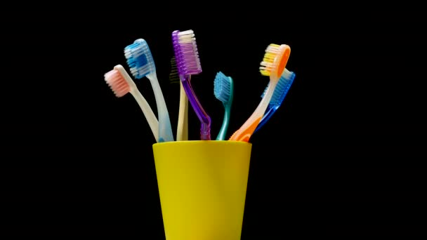 黄色のケースの歯ブラシのクローズアップは 黒の背景に回転します 歯のケア 多色の歯ブラシ ターンテーブル上の歯ブラシ 歯科治療 — ストック動画