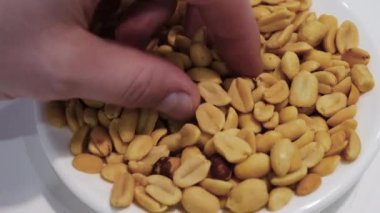Üst manzara tuzlu fıstıkları yakından yemek. Adamın eli fıstıklı baklagilleri yiyor. Genç bir adam enerjisini fındık yiyerek toplar.