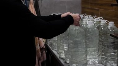 Ukrayna 'daki savaş sırasında su kaynakları. Bir kişi bir dairede su depoluyor ya da stokluyor. Savaş sırasında içilen suyla dolu bir sürü plastik şişe.