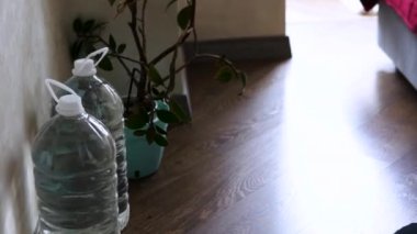 Bir adam dairesinde şişe su depoluyor, Ukraynalı bir adam savaşın ortasında ülkede su sıkıntısı varken su depoluyor. Bir adam kileri su şişeleriyle dolduruyor. Su kaynağı acil bir durum.