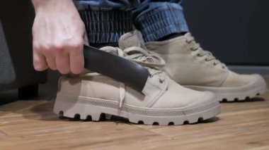 Yakın plan genç adam bacağına modern ayakkabılar giyer, gri erkek ayakkabıları bağlar. Adamın elleri ayakkabıları bağlıyor. Erkek çizmeleri.