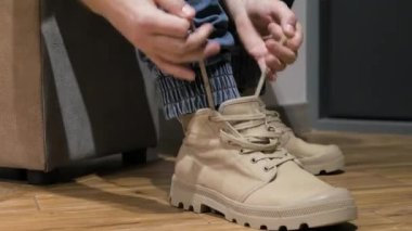 Genç bir adam bacağına ayakkabı giyer, erkek gri ayakkabıları giyer. Erkek çizmeleri.