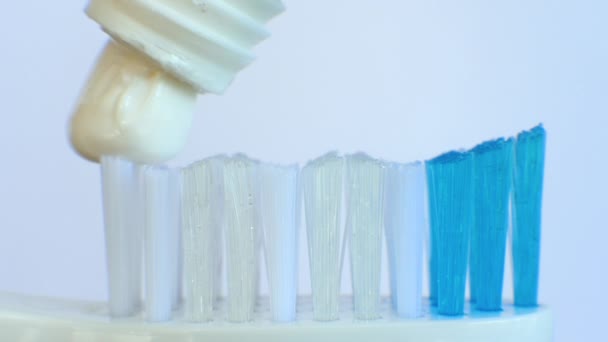 Drücken Sie Weiße Zahnpasta Auf Eine Kunststoffzahnbürste Auf Weißem Hintergrund — Stockvideo