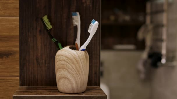 バスルームでケースに歯ブラシを入れてください 彼の手で男は歯を磨くための木製のエコ歯ブラシを置く — ストック動画