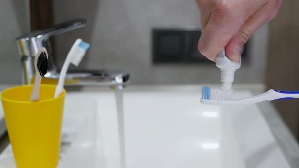 Menselijke Handen Knijpen Tandpasta Uit Een Tandenborstel Boven Een Gootsteen — Stockvideo