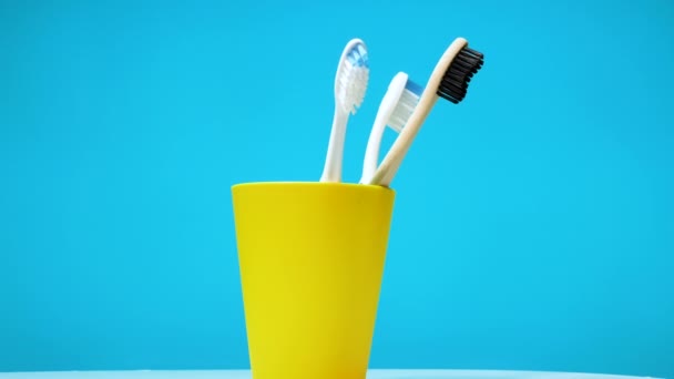 一套牙刷在一个蓝色背景的转盘上旋转着 在一个黄色塑料盒工作室拍摄的牙刷 — 图库视频影像