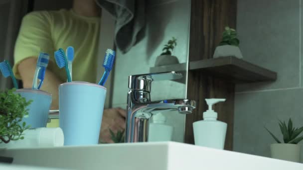 若い男は彼の歯を磨くためにバスルームに入り 白い歯の概念は 男はバスルームで彼の歯を磨く 手でケースの歯ブラシを取ります 口腔ケア — ストック動画
