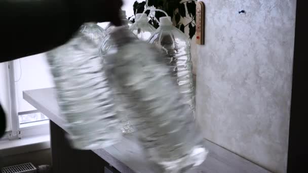 绝望的人把饮用水储存在瓶子里 公寓里稀缺的饮用水的供应 一个男人留了许多水瓶供他饮用或烹调 — 图库视频影像