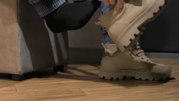 若い男が男の足にスペードのグレーの靴を履いている メンズブーツ — ストック動画