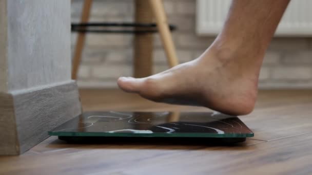 床の上に男の裸の足が立っている 人は体重計で量られます 減量の概念 — ストック動画
