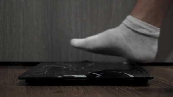 男性の足は床のスケールに立つ 人は体重を制御するために体重計で測定されます 体重ケアの概念 — ストック動画