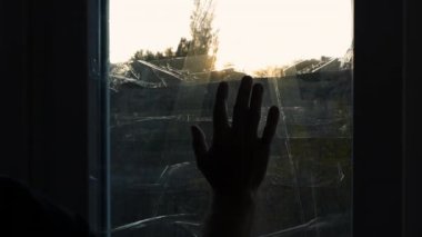 Bir adamın eli pencerenin camının üzerinde kayar, pencereler roket patlaması bandıyla kaplıdır. Ukrayna 'da askeri bunalımda olan bir adam. Pencereler bantla kapatılmış. Yaşlı bir adam elleriyle pencereye dokunuyor.