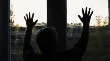 Bir kadın evinde roket patlamalarından saklanıyor. Ukrayna 'da savaş bunalımında olan bir kadın. Pencereler patlama dalgasının yapışkan bandıyla kapatılmış. Yaşlı kadın elleriyle pencereye dokunuyor, üzgün kadın.