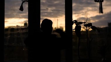 Depresyondaki bir adam, patlama dalgasından korunmak için mühürlü pencerelerin arkasına yaslanır. Evde savaştan saklanan bir adam bulunur. Depresyondaki bir adam dairedeki pencere camına elini sürdü.