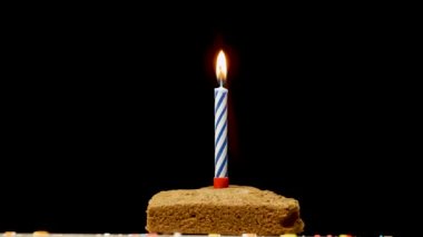 Siyah arka planda yanan mumlarla şenlikli pasta. Yıldönümü pastası. Doğum günü süslemeleri ve masada iştah açıcı bir turta.