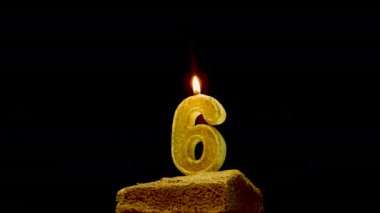  Kutlama pastası, üzerinde 6 numaralı mum olan yakın çekimde siyah bir arka plan. Yıldönümü pastası. Masada iştah açıcı bir turtayla bir doğum günü süslemesi dönüyor.