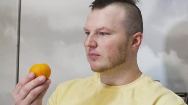 Bir insan sağlıklı meyve mandalinasının tadını çıkarır. Mandalina kabuğunu soy ve C vitamini ile sağlıklı bir meyve ye.