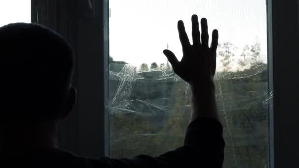 一个人的手从窗户的玻璃上滑过 窗户上布满了火箭爆炸的苏格兰胶带 一个在战争期间在乌克兰的男人窗户是用防爆胶带密封的 一位老人用手触摸着窗户 — 图库视频影像